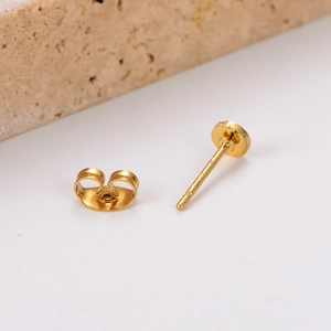 Set of minimalist geometric gold stud earrings with butterfly backings on stone