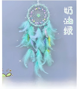 Detail of bohemian creamy green dreamcatcher with colorful beads and soft feathers