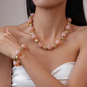 Detail of pink acrylic square beads and irregular gold metal accents on necklace set