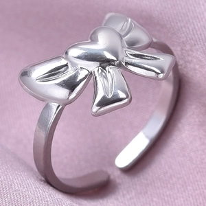 Macro d'une bague papillon argentée sur un fond de tissu en soie rose doux
