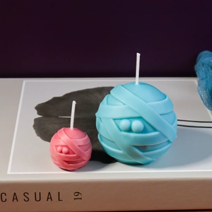 Makroaufnahme von blauen und rosa Mumien-Kugelkerzen mit Bandagentextur auf Büchern