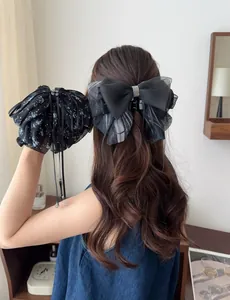 Detail of elegant black chiffon bow hair claw with sparkling rhinestones and floral streamers