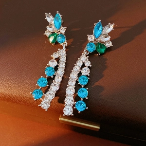 Detail of silver drop earrings with blue and green crystals on a leather jewelry box
