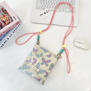 Close-up of cream butterfly jacquard crossbody bag on a white desk with lifestyle props