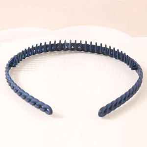 Deep blue matte plastic headband with fine comb teeth on a white aesthetic tray