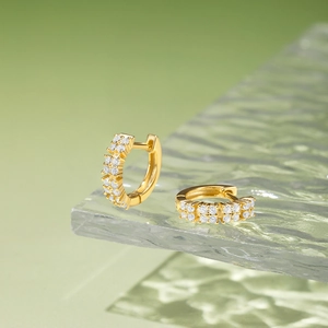 Macro detail of gold-plated Huggie hoop earrings with double row paved zircons on glass