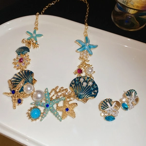 Flat lay of gold starfish and seashell necklace set with pearls and turquoise rhinestones