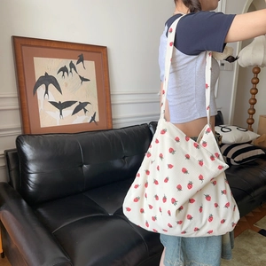 Gros plan du sac cabas en velours côtelé à imprimé fraise porté par un modèle