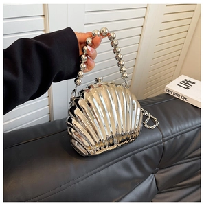 Detail of silver shell-shaped evening bag with glossy metallic finish and beaded handle