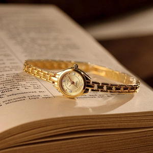 Elegant gold quartz watch for women with round dial on a vintage book backdrop