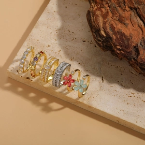 Set di sei anelli oro e argento con fiori e zirconi su base di marmo