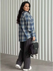 Side view of a loose checkered shirt paired with wide-leg pants and a textured backpack