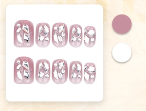 Detail of pink press-on nails with silver glitter, rhinestones, and pearls on white board