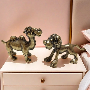 Antique brass camel and lion figurines set on a pink nightstand for home decoration