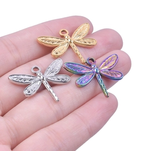 Macro shot of dragonfly charms in gold, silver, and rainbow colors on a palm