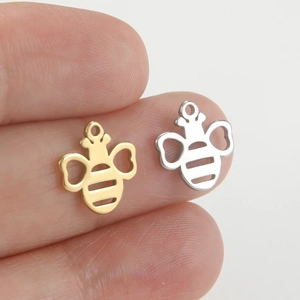 Detail of small bee-shaped metal pendants in gold and silver finish for jewelry