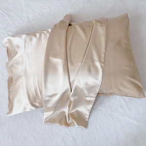 Detail of a champagne silk pillowcase with glossy texture laid on white plush background
