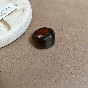Detail of amber resin oval ring with glossy finish on natural craft paper background