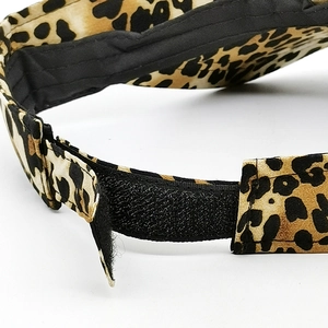 Close-up of leopard print sun visor featuring adjustable black hook and loop fastener strap