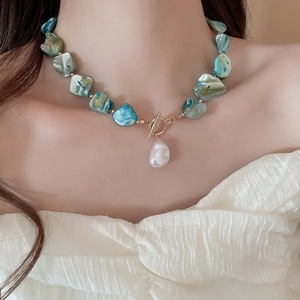 Detail of bohemian necklace with irregular turquoise beads and baroque pearl on a model