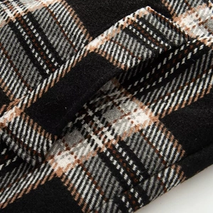 Detailaufnahme des schwarz-weiß-braunen Karomusters und der Wolltextur des Mantels