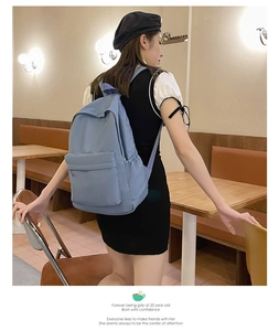 Lifestyle shot of a light blue large capacity backpack on a model in a cozy cafe setting