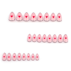 Faux ongles amande avec motifs de cœur rouge et bordures à pois noirs et blancs