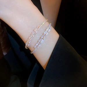Bracelet jonc argenté luxueux orné de zircons sur un poignet avec costume noir chic
