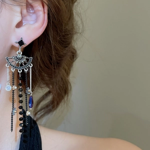 Close-up of sparkling crystal flower earrings with blue water drop tassels on a model