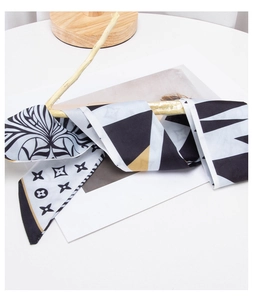 Close-up of retro silk ribbon scarf with black and white floral and geometric patterns