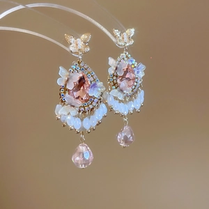 Detailed close-up of pink crystal tassel earrings with golden butterfly and beads