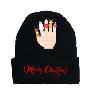 Close-up of a black knit Christmas beanie featuring festive text and holiday patterns