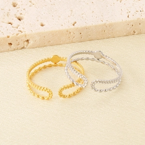 Detail of gold and silver double-layered beaded rings on a beige textured stone base