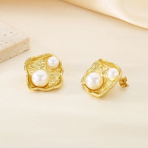 Vue détaillée des boucles d'oreilles en acier doré avec texture lave et perles blanches chic