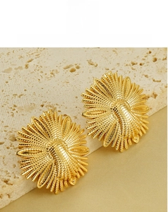 Close-up of golden sunflower earrings on a stone textured surface showing metal details