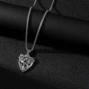 Gros plan d'un pendentif bouclier argenté avec un ange ailé sur une chaîne de type box