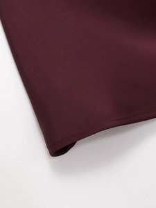 Detailed macro view of the burgundy satin top featuring reinforced double-stitched hemline