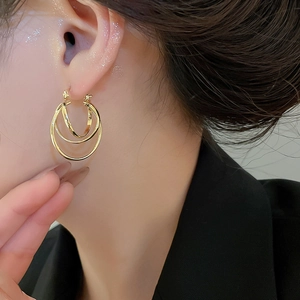 Close-up of golden multi-layer round hoop earrings worn by a model for elegant style