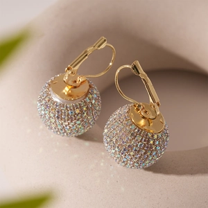 Gros plan détaillé de boucles d'oreilles boules dorées ornées de strass multicolores