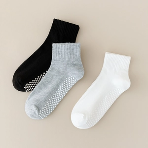 Detail showing anti-slip silicone grippers on the soles of black, grey, and white socks