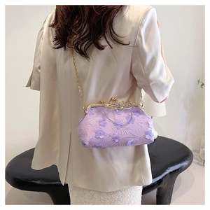 Detail of lavender floral embroidery on elegant clutch bag with gold chain strap