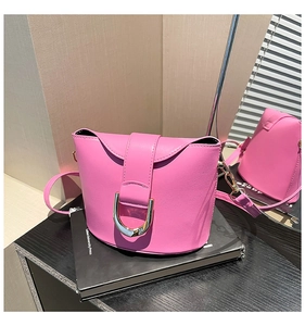 Detailed close-up of rose pink leather bucket bag featuring a gold horseshoe buckle