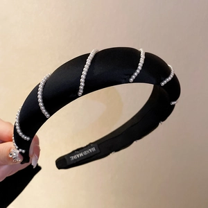 Detail of handmade black satin headband with white pearl embellishments and inner tag