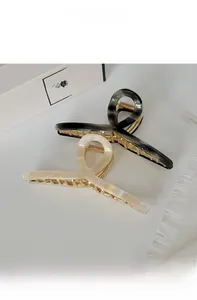 Detail of large marble and pearl texture hair claws with gold metal spring components
