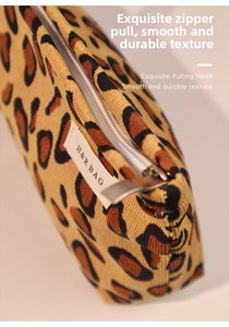 Detail of leopard print corduroy makeup bag showing the smooth metal zipper and brand label