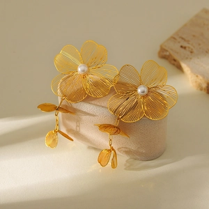 Detail of gold flower earrings with pearls and petal tassels on a stone pedestal