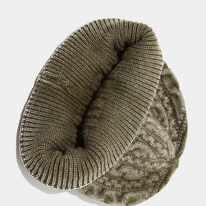 Gros plan sur un bonnet vert olive en maille torsadée avec texture épaisse et bord côtelé