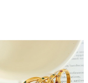 Detailed macro view of gold-plated rings with red, green and white inlaid gemstones