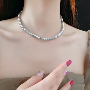 Detail einer silbernen Perlenkette am Hals für einen eleganten französischen Retro-Stil