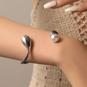 Detailed close-up of a silver titanium steel open bangle with a pearl and teardrop design